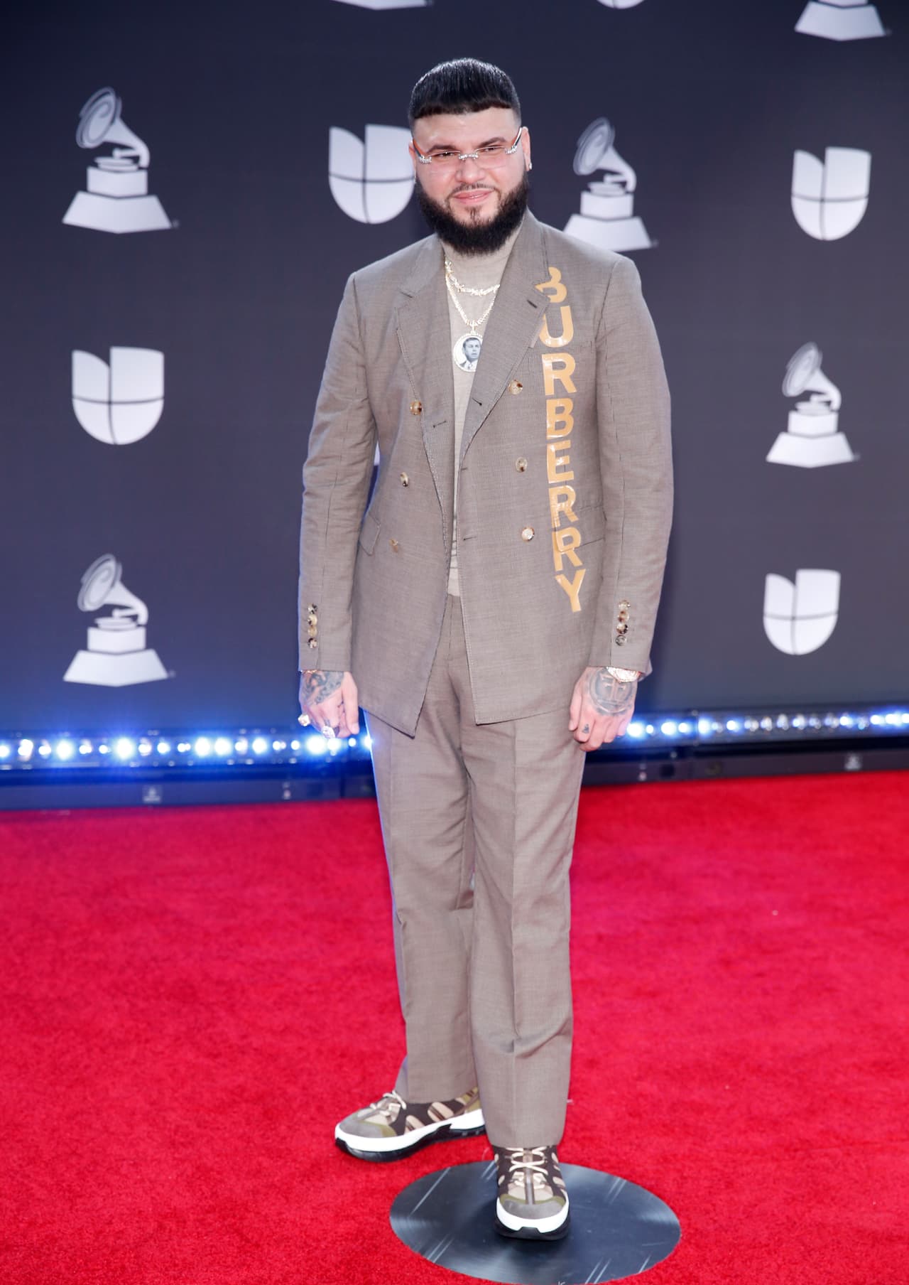 Farruko mezcló un conjunto Burberry con tenis y accesorios plateados.
