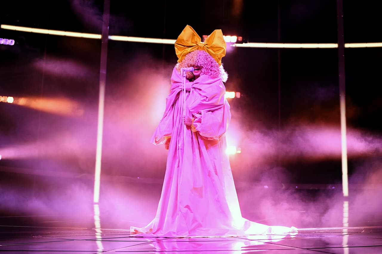 Uno de los atuendos más extravagantes de la noche fue el de Sia.
<br>
<br>La intérprete de "Chandelier" se mostró cubierta con un vestido gigante, rosa, un moño enorme, amarillo y cabello chino en dos tonos de rosado. Esta pieza es de Dolce & Gabbana
<b>.</b>