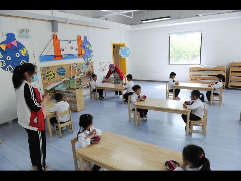 Hasta en los salones de clase respetan la sana distancia. En esta foto se puede ver a los niños comiendo una fruta del dragón muy separaditos.