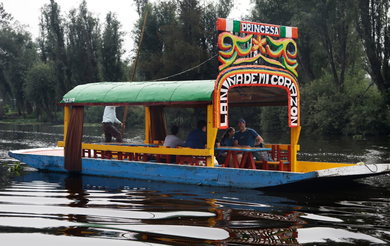 In this July 13, 2017 photo, tourists ride in a "trajinera" on a canal in Xochimilco, Mexico City. A late July report by the Universidad Autonoma Metropolitana (UAM), in collaboration with local NGO Controla tu Gobierno, indicates that most of the water being fed into Xochimilco’s canals comes from a water treatment plant known as Cerro de la Estrella, whose output contains “a high level of fecal coliform that indicate sewage.” (AP Photo/Marco Ugarte)