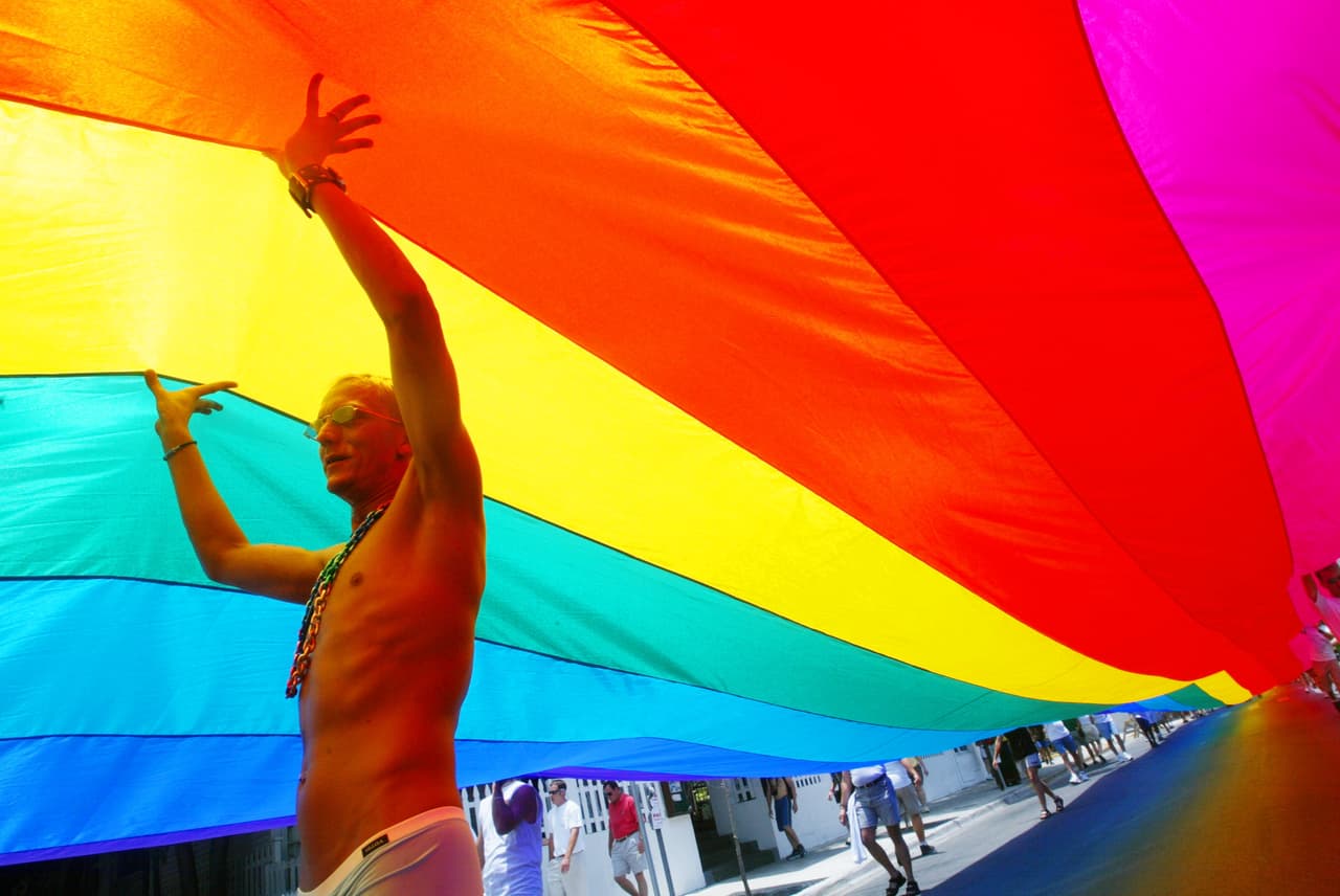 KEY WEST, FL - JUNE 15: Bobbie Schrum helps stretch the mile and quarter long "World's Longest Rainbow Flag" June 15, 2003 from the Gulf of Mexico to the Atlantic coast along Duval street in Key West, Florida. The flag was created for Rainbow25 and PrideFest Key West. The Record setting flag measures 8,000 feet long by 16 feet wide and used more than 14,000 square yards of fabric. (Photo by Joe Raedle/Getty Images)