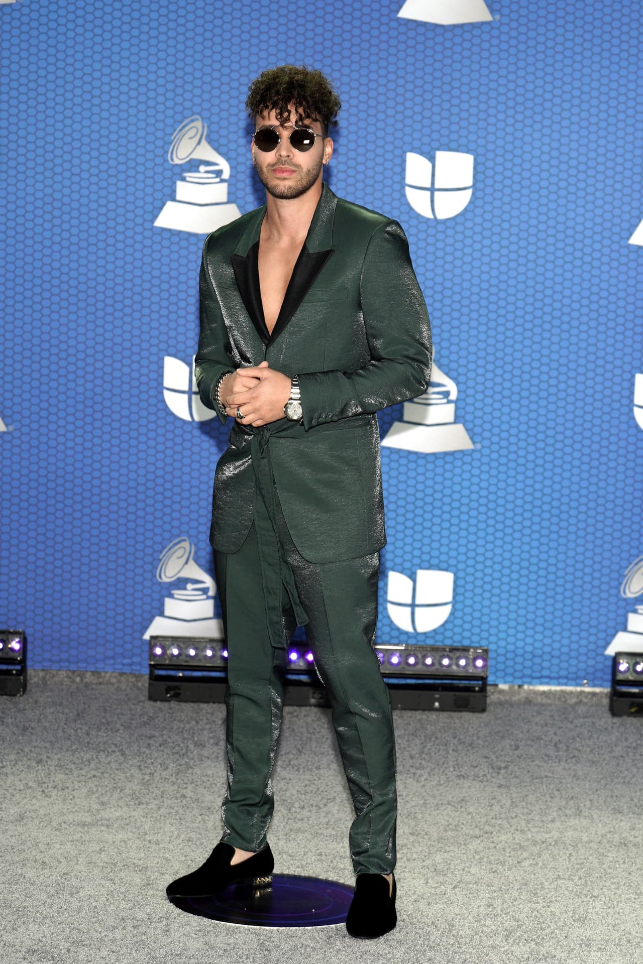 La noche más importante de la música latina comenzó con la llegada de las celebridades a la alfombra roja en Miami, Florida, para mostrar sus mejores outfits. Uno de los primeros fue Romeo Santos, quien posó con lentes oscuros y un atuendo muy estiloso, con una camisa a pecho medio abierto y un saco.