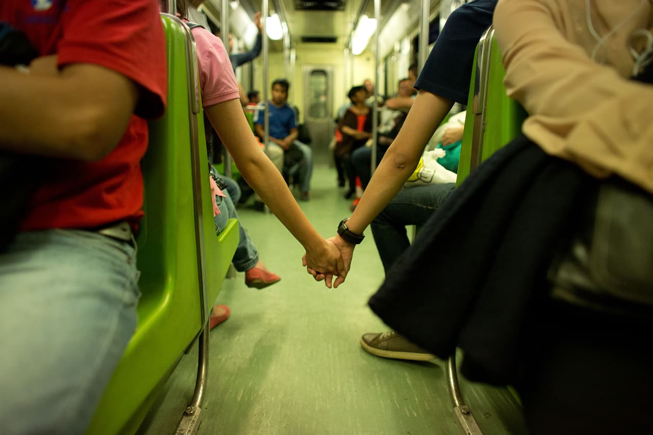 In this Thursday, Sept. 18, 2014 photo, a young couple, unable to find seats together in the metro, hold hands across the aisle at the start of evening rush hour in Mexico City. (AP Photo/Rebecca Blackwell)