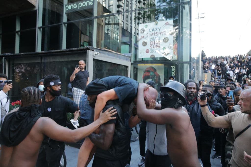 LONDON, UNITED KINGDOM - JUNE 13: A group of men including Patrick Hutchinson (carrying the man) help an injured man away after he was allegedly attacked by some of the crowd of protesters on the Southbank near Waterloo station on June 13, 2020 in London, United Kingdom. Following a social media post by the far-right activist known as Tommy Robinson, members of far-right linked groups have gathered around statues in London. Several statues in the UK have been targeted by Black Lives Matter protesters for their links to racism and the slave trade. (Photo by Luke Dray/Getty Images)