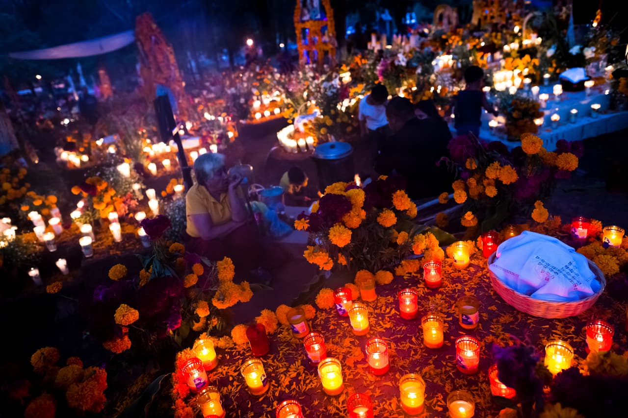 TZINTZUNTZAN, MEXICO - NOVEMBER 02: Mexican family members light candles and pray at the cemetery to honor their deceased relatives during the Day of the Dead celebration on November 02, 2014 in Tzintzuntzan, Mexico. Day of the Dead is a syncretic religious holiday, celebrated throughout Mexico, combining the death venaration rituals of the ancient Aztec culture with the Catholic practice. Based on the belief that the souls of the departed may come back to this world on that day, people gather on the gravesites praying, drinking and playing music, to joyfully remember friends or family members who have died and to support their souls on the spiritual journey. (Photo by Jan Sochor/Latincontent/Getty Images)