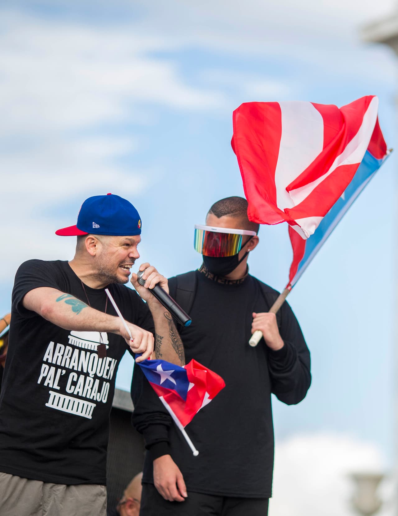 Puerto Rican rapper Rene Juan Perez known by his stage name of Residente, left, speaks to the crowd, accompanied by Benito Antonio Martinez Ocasio, known by his stage name Bad Bunny, in front of the Puerto Rican Capitol, before a protest march against governor Ricardo Rosello, in San Juan, Puerto Rico, Wednesday, July 17, 2019. Protesters are demanding Rossello step down for his involvement in a private chat in which he used profanities to describe an ex-New York City councilwoman and a federal control board overseeing the island's finance. (AP Photo/Dennis M. Rivera Pichardo)