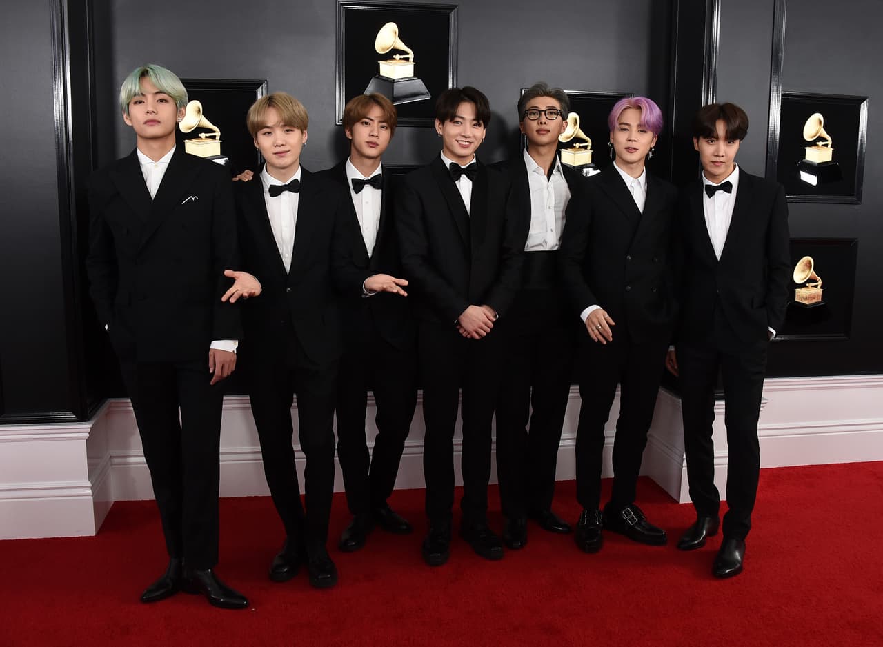 BTS también sabe cómo verse bien en un aspecto formal con esmoquin color negro, camisa blanca y moños negros que reflejan estilo y seguridad.