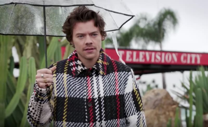 En ese mismo programa, Harry apareció con un abrigo Lanvin a cuadros, acompañado de un paraguas transparente para protegerse de un inusual día lluvioso en Los Ángeles.